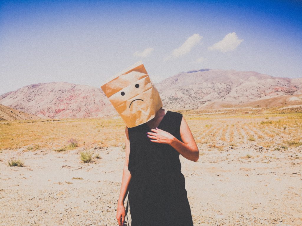 Person standing in the desert with a bag over their head because they made a freelance writing mistake.