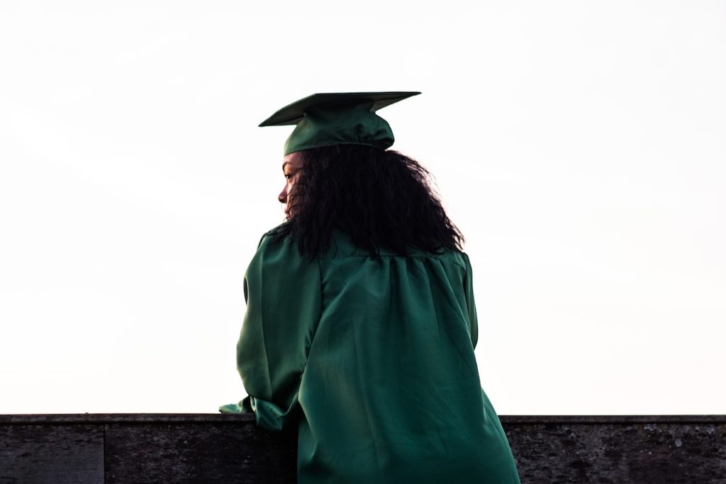 College graduate leaning over a railing and thinking of what to do next in her life.