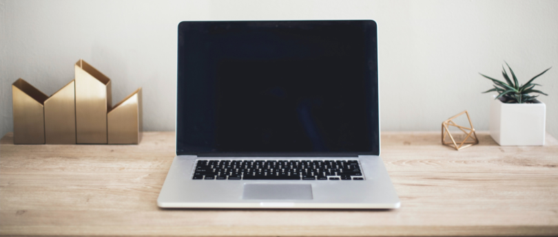 Open MacBook with blank screen on desk.